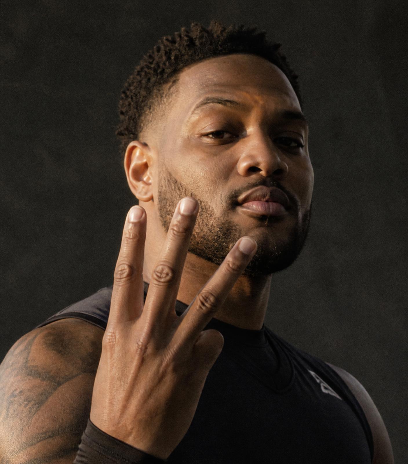 A Black participant holds up three fingers after completing three personal check-ins.